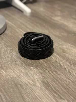 Flätat svart marc’o polo bälte - Snyggt flätat svart bälte från marc’o polo i äkta läder. Bältet har en klassisk silverfärgad metallspänne och passar perfekt till jeans eller byxor för en stilren look. Enkel att justera tack vare det flätade mönstret.