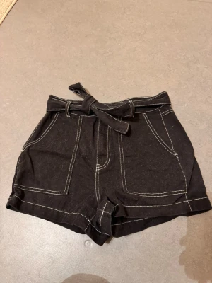 Jeansshorts med kontrastsömmar - Söta och coola jeansshorts med kontrastsömmar. Inte mycket använda. De har ett band att knyta i midjan. Storlek 38.