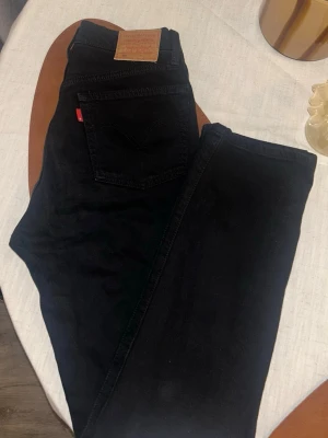 Svarta Levi's jeans med rak passform - Säljer ett par svarta Levi's jeans med klassisk rak passform och fem fickor. Jeansen har den ikoniska röda Levi's-lappen på bakfickan och detaljer i kopparfärg. 🖤 längd:30