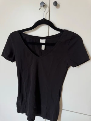 HM basic topp, v formad hals  - Säljer denna svarta topp från Hm basics med V-formad hals, perfekt för vår/sommar🖤Tröjan är knappt använd och därför i perfekt skick👌