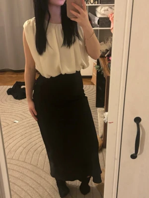 Zara Svart/vit lånklänning - Säljer en svart långklänning med hög midja och rak passform. Klänningen är enkel och stilren, perfekt för dig som gillar minimalistisk stil. Materialet känns mjukt och följsamt, troligen polyester eller liknande. Passar till många olika looks.