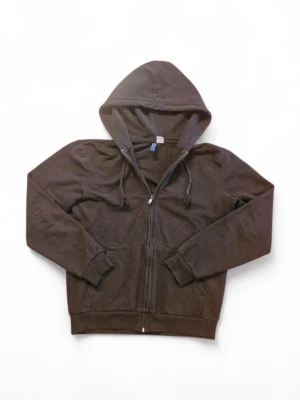 Svart zip-hoodie med dragsko - En klassisk svart hoodie med dragkedja framtill och huva med dragsko. Modellen har långa ärmar, ribbade muddar och fickor på sidorna. Perfekt för en avslappnad stil och enkel att matcha med andra plagg.