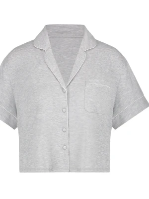 Hunkemöller grå pyjamastopp - Grå pyjamastopp med korta ärmar och krage. Toppen har knappar framtill och en bröstficka. Vita passpoaler löper längs kragen, knappslån, ärmsluten och bröstfickan. En text finns tryckt i nacken.