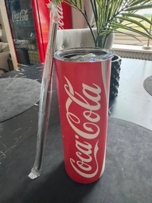 Coca-Cola termosmugg 0.6L - Cool röd termosmugg från Coca-Cola med klassisk logga och lock. Muggen är cylinderformad och har ett medföljande stålsugrör & piprensare. Perfekt för kalla  eller varma drycker och enkel att ta med överallt. Rymmer 20oz / ca 0.6L.