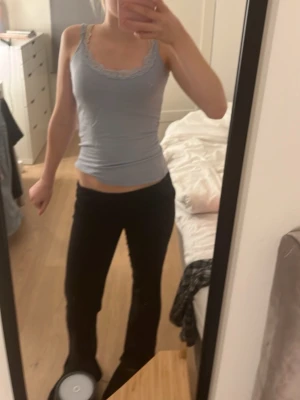 Ljusblå linnetopp med spetskant - Säljer en ljusblå linnetopp med smala axelband och dekorativ spetskant längs halsringningen. Toppen är croppad och har en slim passform som framhäver figuren. Perfekt för dig som gillar en enkel och söt stil. Kan även användas som nattlinne, linnet har ett mjukt och lent material.