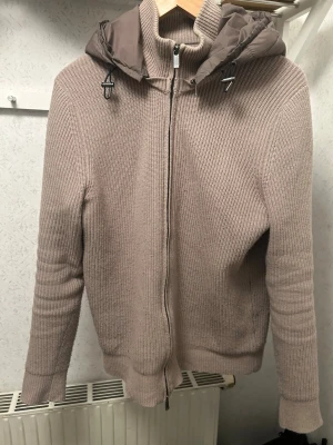 Massimo dutti cardigan - Beige stickad jacka från Massimo dutti som inte säljs något mer med dragkedja och vadderad huva i matchande färg. Tröjan har ribbstickad struktur, långa ärmar och justerbar huva med snörning. Perfekt nu inför våren och även lager-på-lager.