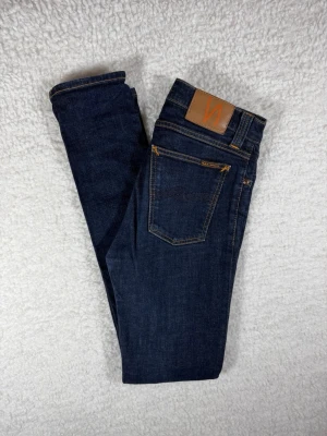 Nudie jeans high Kai  - Snygga mörkblå skinny jeans från Nudie Jeans med klassisk femficksmodell och kontrastsömmar. Jeansen har en hög midja och är tillverkade i stretchigt denim för en bekväm passform. Perfekta till alla dina favoritoutfits!
