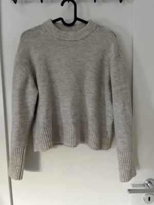 Beige stickad tröja Gina Tricot - Mysig beige stickad tröja från Gina Tricot med rund halsringning och ribbade muddar. Modellen är lite kort i långden Storlek 146/152 Använd ett par gånger 