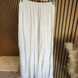 Vit långkjol från stradivarius  - Luftig och flowy vit långkjol i mjuk bomull. Kjolen har en enkel design med resår i midjan och lätt rynkade partier som ger en avslappnad och bohemisk känsla. Perfekt för varma dagar och enkel att matcha med olika toppar.