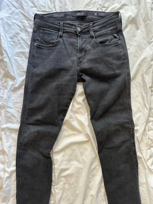 Svarta jeans från Replay - Snygga svarta jeans från Replay med klassisk femficksdesign och diskret Replay-logga vid fickan. Jeansen har dragkedjegylf och är tillverkade i stretchigt denim för en bekväm passform. Perfekta för en trendig och avslappnad stil. Storlek 30