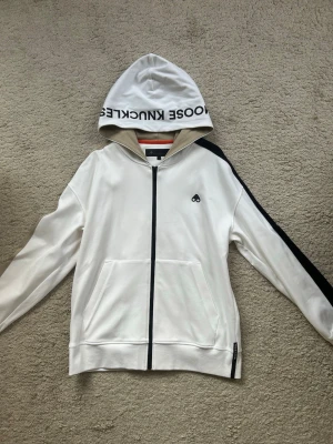 MooseKnuckles Hoodie - MooseKnuckles Zip hoodie som är köpt på Zgander i Helsingborg. Tröjan är aldrig använd och är i ny skick, Storlek Medium men är stor i storleken så passar även Large. Hoodien + T shirt är 1000kr!