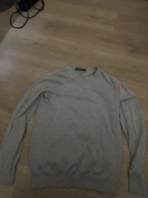 Ljusgrå stickad tröja - En stilren ljusgrå stickad tröja med rund halsringning och långa ärmar. Perfekt  att matcha med olika outfits