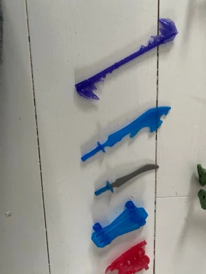 Teenage Mutant Ninja Turtles figurer - Fyra actionfigurer av Teenage Mutant Ninja Turtles i grönt med tillhörande plastvapen i blått, lila, rött, orange och silver. Figurerna har detaljerade skal och färgade bandanas. Vapnen inkluderar svärd, stavar och andra klassiska tillbehör. Perfekt för samlare eller lek.