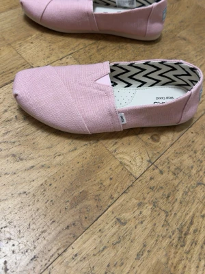 Rosa loafers från TOMS - Jag säljer ett par rosa TOMS-skor i mycket fint skick. Skorna är bekväma, stilrena och nästan som nya. Perfekta till vardag, vår och sommar.    Hör gärna av dig vid intresse eller om du vill ha fler bilder.