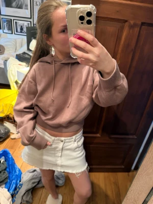 Brun croppad stickad hoodie med huva - Säljer en croppad hoodie i en snygg brun nyans. Hoodien har huva med dragsko och breda muddar vid ärmsluten. Matrialet är extremt mjukt 