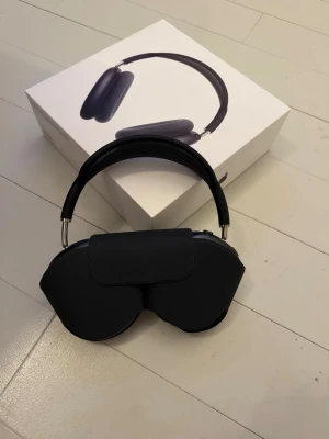 Apple AirPods Max 2025 Midnatt - Snygga och moderna Apple AirPods Max i svart med stilren design. Over-ear hörlurar med mjuka öronkuddar, metallbyglar och meshband för extra komfort. Perfekta för musik, gaming eller videos. Levereras med originalförpackning och smart case.