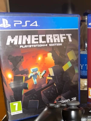 Minecraft PlayStation 4 Edition - Minecraft PlayStation 4 Edition är ett ikoniskt sandlådespel där du kan bygga, utforska och överleva i en blockig värld. Omslaget är färgglatt med pixelgrafik och spelet kommer i ett blått PS4-fodral. Perfekt för kreativa spelare som gillar äventyr.