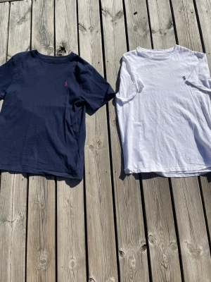 Polo Ralph Lauren t-shirts  - Tjena! Säljer två stycken polo T-shirts som är perfekta till sommaren. Båda är i använt skick men utan fläckar eller hål. Den marinblåa är i storlek S och den vita t-shirten är i storlek M. Går att köpa tillsammans eller separat. Skriv om det finns några funderingar och priset är inte hugget i sten🥂