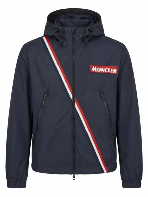 Moncler marinblå vindjacka med huva - Snygg marinblå vindjacka från Moncler med huva och dragkedja. Jackan har en diagonal röd, vit och blå rand samt Moncler-logga på bröstet. Två snedställda fickor med dragkedja. Perfekt för en sportig och stilren look.