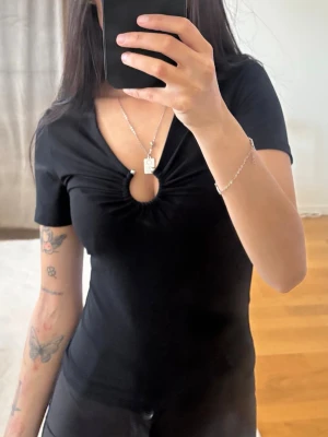 Fin topp - Svart kortärmad topp med snygg cut-out och rynk framtill vid bysten. V-ringad och figurnära passform som ger en trendig look. Nyskick💕