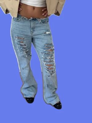 Ljusblå slitna raka jeans med kedjdetaljer  - Lowwaist jeans med unika slitningar och kedjor vid hålen. Midja: 40-42cm Innerbenslängd: 75cm 