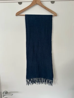 Mörkblå Scottsberry halsduk i 100% ull - Klassisk mörkblå / marinblå / navy yllehalsduk från Scottsberry Stockholm. Eleganta fransar i ändarna, och en klassisk och stilren look. 100% ull. Mycket gott skick. Nypris 799:-.  Skickas mot porto eller hämtas i Stockholm.