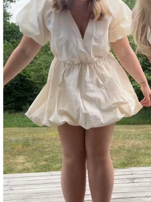 Vit kort klänning med puffärm - Supersöt vit kort klänning med puffiga ärmar och v-ringning. Klänningen har en luftig passform och markerad midja som ger en fin siluett. Perfekt för studenten!!!