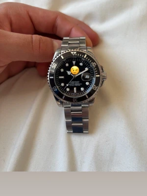 Klassisk silverfärgad klocka - Snygg och tidlös klocka med svart urtavla och datumvisning. Armbandet är i silverfärgat metall och boetten har en markerad vridring. Perfekt accessoar för dig som gillar stilrena detaljer.