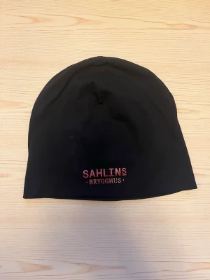 Svart tränings mössa Sahlins Brygghus - Svart mössa med trycket 'Sahlins Brygghus' framtill perfekt till träning utomhus.  Mössan är designad i Sverige och passar perfekt för kalla dagar.