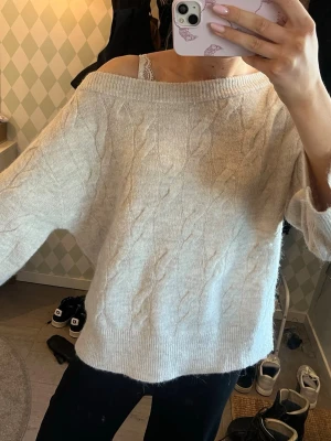 Off shoulder tröja  - Säljer en beige kabelstickad tröja med bred off shoulder-ringning och avslappnad passform.