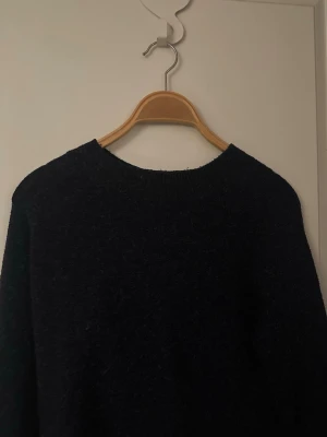 Mörkblå stickad tröja Vero Moda - Mysig mörkblå stickad tröja från Vero Moda med rund halsringning och lång ärm. Perfekt för kalla dagar och enkel att matcha med jeans eller kjol. Klassisk modell utan mönster och med ribbade muddar vid halsen.