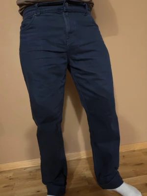 Timberland herrbyxor  - Snygga mörkblå chinos med avsmalnande ben och klassisk passform. Byxorna har bälteshällor, knappgylf och sidofickor. Perfekta för en clean och stilren look. Materialet känns mjukt och följsamt, vilket gör dem bekväma att bära hela dagen.