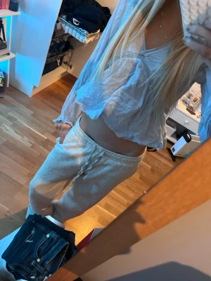 Ljusblå volangblus med omlott - Säljer en ljusblå blus med omlottdesign och volangdetaljer. Blusen är croppad, har v-ringning och långa ärmar. Tillverkad i ett tunt och luftigt material som ger en chill och trendig vibe.