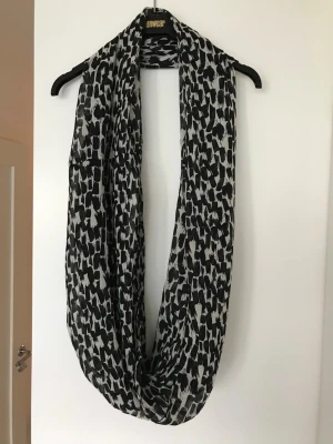 Svartvit mönstrad rund sjal ny.. - Säljer en svartvit rund sjal med abstrakt mönster. Sjalen är i ett tunt, mjukt material som känns luftigt och skönt runt halsen. Perfekt accessoar för att lyfta din outfit med en cool touch.