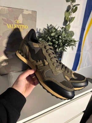 Valentino Garavani camo sneakers - Snygga sneakers från Valentino Garavani i militärgrönt camomönster med svarta och beige detaljer. Skorna har meshpaneler, mocka och läderpartier samt en beige sula med svarta inslag. Perfekta för dig som vill sticka ut med stil.