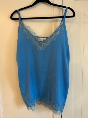 Blå linnetopp med spets  - Snygg blå linnetopp från Saint Tropez med tunna axelband och dekorativ spets vid ringningen och nederkanten. Perfekt att styla till jeans eller kjol för en fräsch look. Materialet känns mjukt och lätt mot huden. Knappt använd!❣️