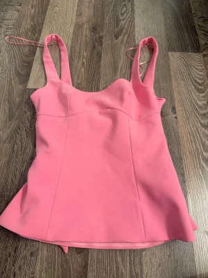 Rosa linnetopp med rosett - Supersöt rosa linnetopp med breda axelband och en stor rosett i ryggen. 