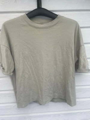 Beige basic t-shirt i bomull - Enkel beige t-shirt med rund hals och uppvikta ärmar. Tillverkad i mjuk bomull och har en avslappnad passform som passar till det mesta. Perfekt för dig som gillar minimalistisk stil. Väl använd men ej fläckar storlek och märke vet ej