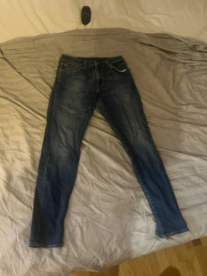 Levi's 512 blå jeans W30 L32 - Säljer ett par klassiska blå Levi's 512 jeans med smal passform och normal midja. Jeansen har fem fickor, dragkedjegylf och är tillverkade i slitstark denim. Perfekta för en avslappnad och trendig look.