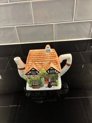 Tekanna i form av hus The Red Lion - Unik tekanna i keramik formad som ett charmigt engelskt hus med texten 'The Red Lion'. Färgerna är mestadels tegelrött, vitt, grönt och svart. Perfekt som dekoration eller till te-stunden. Klassisk och detaljrik design.