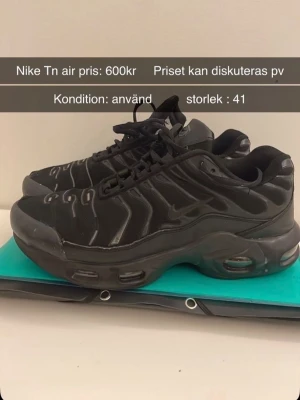 Nike Tn Air helsvarta sneakers - Säljer ett par helsvarta Nike Tn Air sneakers med klassisk vågig design och synliga luftbubblor i sulan. Skorna har svarta snören, diskret swoosh-logga och en chunky sula som ger streetwear-vibe. Materialet är en mix av syntet och mesh för bra komfort