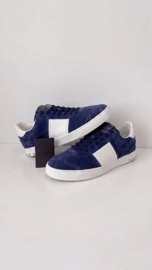 Valentino Flycrew - Snygga sneakers från Valentino i blå mocka med vita detaljer och vit sula. Skorna har en klassisk låg profil, svarta skosnören och coola nitar på hälen. Perfekta för dig som vill sticka ut med stilrena och trendiga skor.