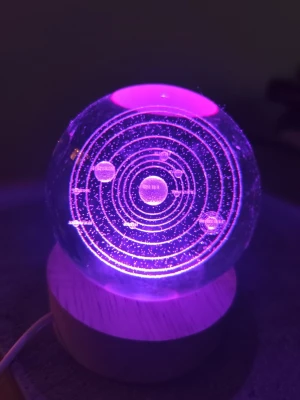 Kristallkula med solsystem och LED-lampa - Cool kristallkula med inristat solsystem som lyser upp i olika färger tack vare LED-lampan i träbasen. Perfekt som dekoration eller nattlampa för rymdintresserade. Kulan är genomskinlig och basen är i ljust trä.