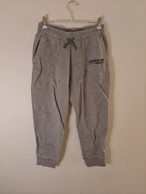 Adidas mjukisbyxor  - Gråa mjukisbyxor från Adidas med resår och dragsko i midjan, samt muddar vid bensluten. Byxorna har två sidofickor och en svart Adidas-logga på vänster ben. Tillverkade i mjukt bomullsmaterial för maximal komfort. Storlek 140 för barn.