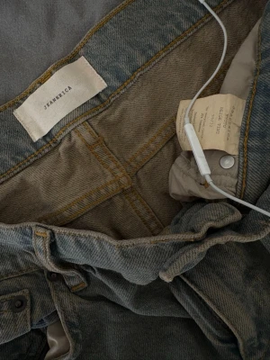 Kyoto vida jeans från Jeanerica  - Säljer ett par snygga vida jeans från Jeanerica i grå tvättad denim. I färgen beige tint. Jeansen har låg midja, raka ben och klassiska fem fickor. Perfekta för dig som gillar en avslappnad och trendig look. Materialet är 100% bomull. W28L32