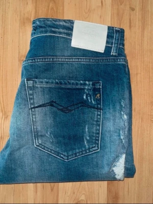 Replay jeans  - Blåa jeans från Replay med snygga slitningar. Midja 38cm, längd 85cm. Obs jeansen längstorlek saknas men jag skulle uppskatta till L28.  JAG SKICKAR EJ FLER BILDER NÄR JAG BÄR JEANSEN! för bättre inblick i passformen rekommenderar jag att googla på modellnamnet. För storleksguide kolla måtten noggrant då jeansen alltid kan vara uppsydda heller krympta och jag ej tar emot returer :) s6,2