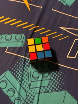 Rubiks kub i klassiska färger - Rubiks kub med klassiska färger: röd, blå, grön, gul, orange och vit. Kuben är i plast och har en svart ram runt rutorna. Perfekt för dig som gillar kluriga pussel och vill utmana hjärnan.