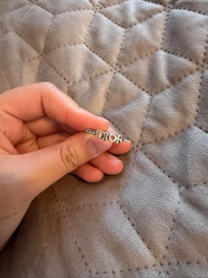 Snygg silverring från Dior - Ring i silverfärg från Dior med gnistrande stenar längs bandet och tydlig DIOR-logga framtill. Perfekt accessoar för dig som gillar exklusiva detaljer och vill sticka ut lite extra. 