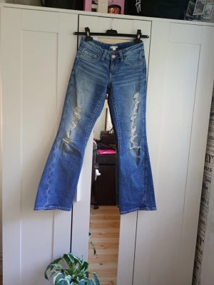 Blå bootcut jeans med slitningar - Säljer ett par blå bootcut jeans dom  har klassisk femficksmodell och är tillverkade i denim. Har finna detaljerade på både fram och baksida. Storleken är 158 cm typ som S eller xs.Perfekta för dig som gillar en avslappnad och trendig stil. 😎💗