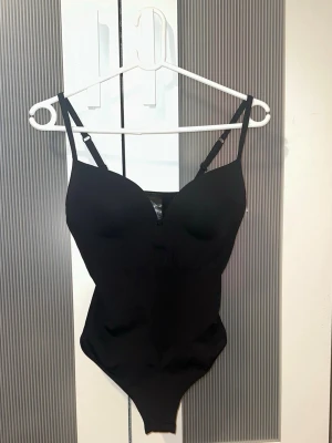 Svart body från H&M trendig - Säljer en svart body från H&M med vadderade kupor och justerbara axelband. Materialet är mjukt och stretchigt. Enkel och stilren design. Slutsåld på flera ställen.     Säljer pga att den är för stor för mig. Annars skitnsnygg och skön. 💗💗